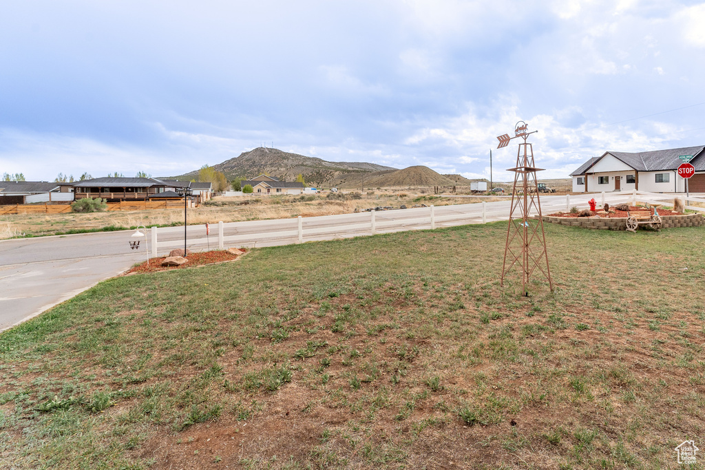 View of yard featuring a mountain view, fence, and driveway
