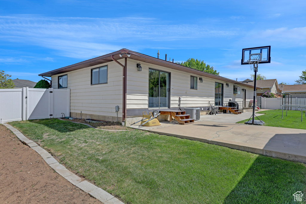 Rear view of house featuring a patio, a gate, a fenced backyard, and a yard