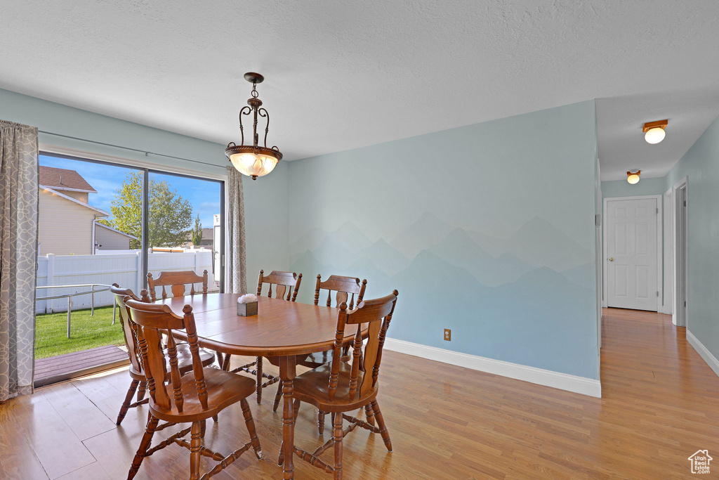 Dining room featuring baseboards, a textured ceiling, and light wood-style flooring