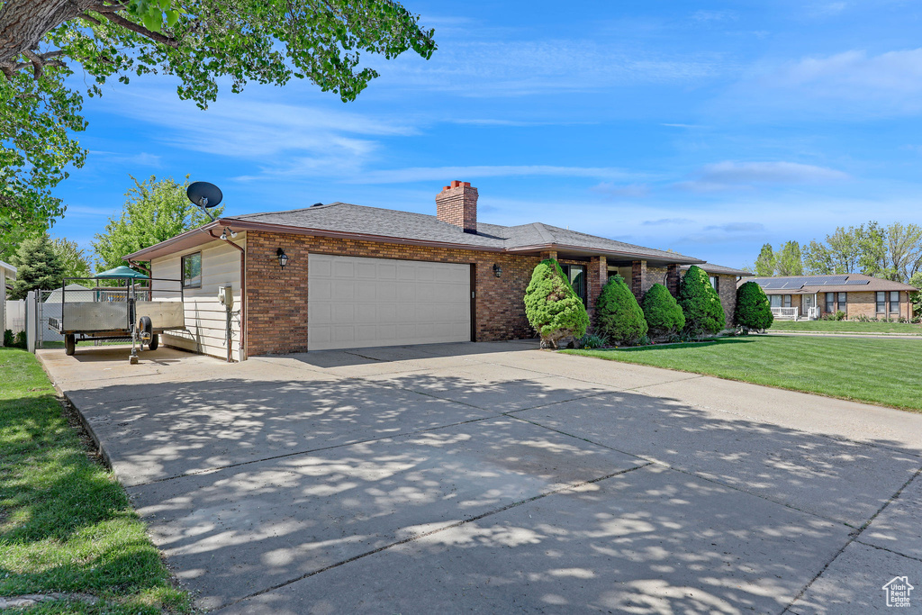 Single story home with a front lawn, brick siding, a garage, a chimney, and concrete driveway