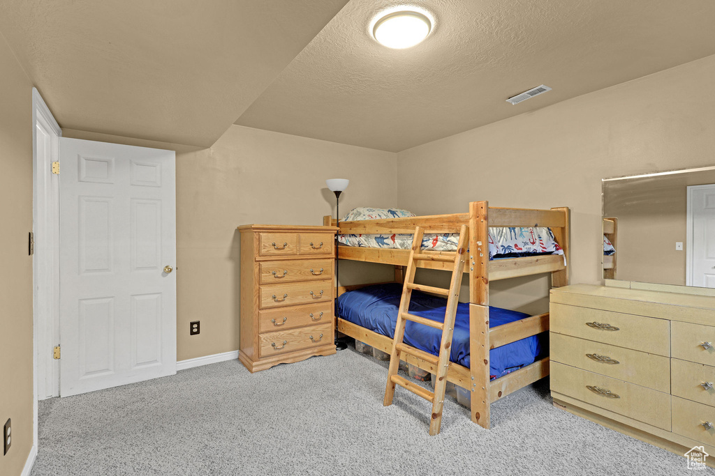 Carpeted bedroom featuring a textured ceiling, visible vents, and baseboards