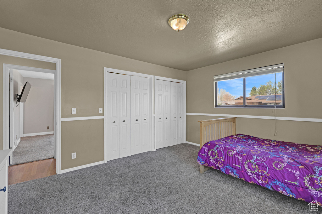 Bedroom with baseboards, a textured ceiling, carpet, and two closets