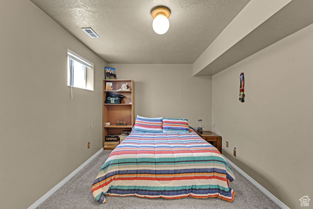 Bedroom with baseboards, carpet, a textured ceiling, and visible vents