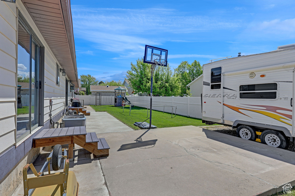 View of patio with a playground and a fenced backyard