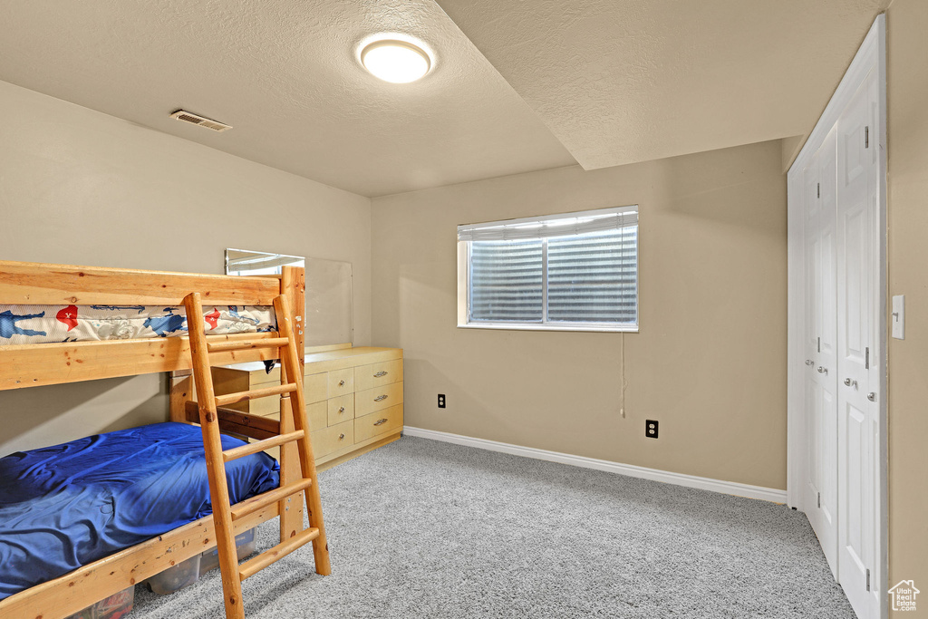 Bedroom featuring carpet floors, baseboards, a textured ceiling, and visible vents