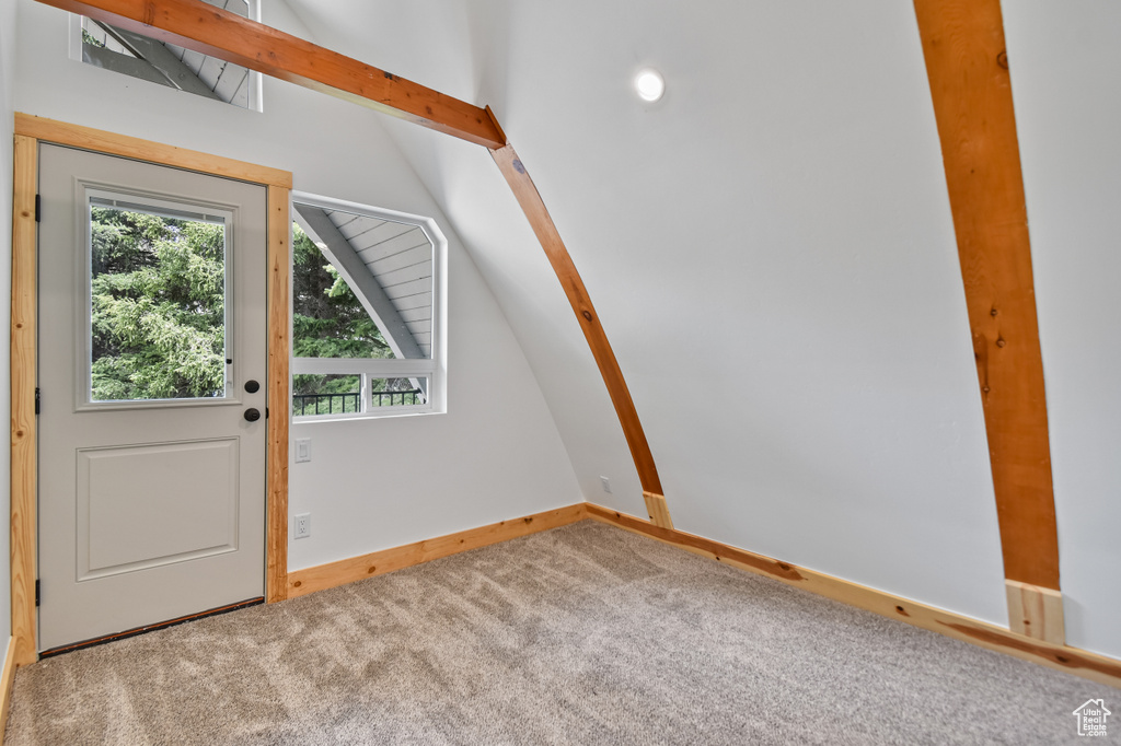 Carpeted entryway featuring baseboards and lofted ceiling