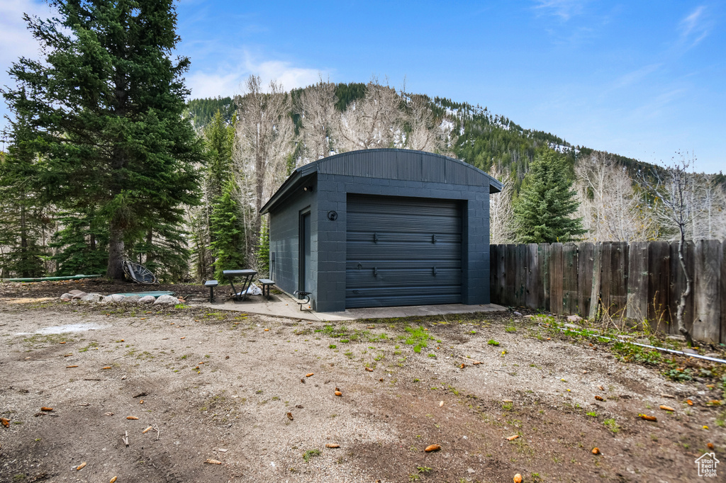 Detached garage with fence, a view of trees, and a mountain view