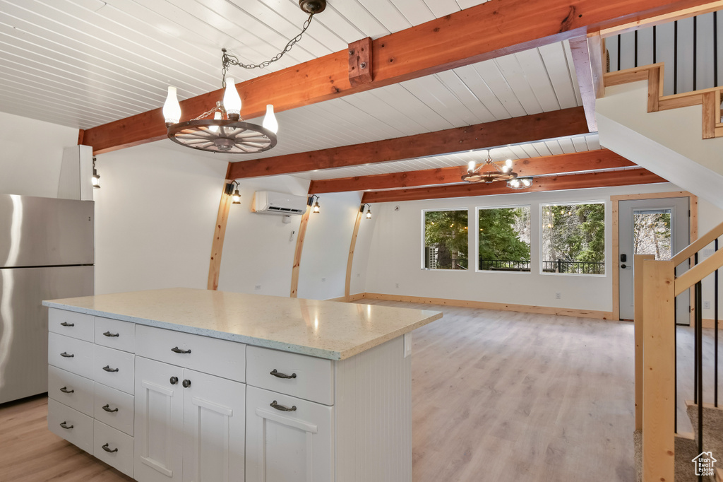 Kitchen featuring beamed ceiling, freestanding refrigerator, a notable chandelier, light wood-style floors, and white cabinetry