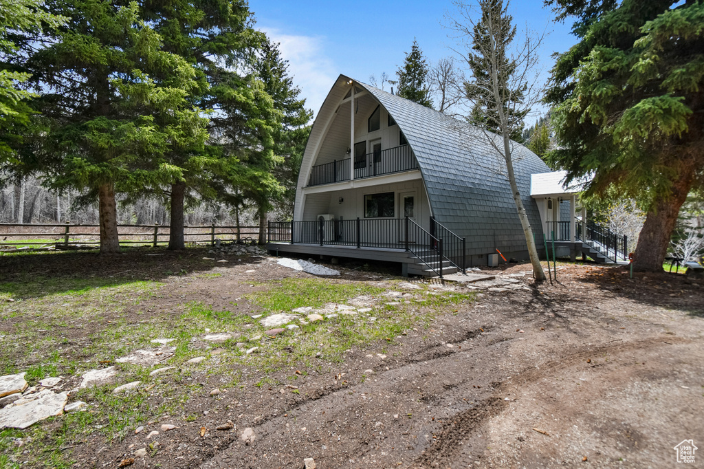Exterior space featuring fence, a gambrel roof, and a balcony
