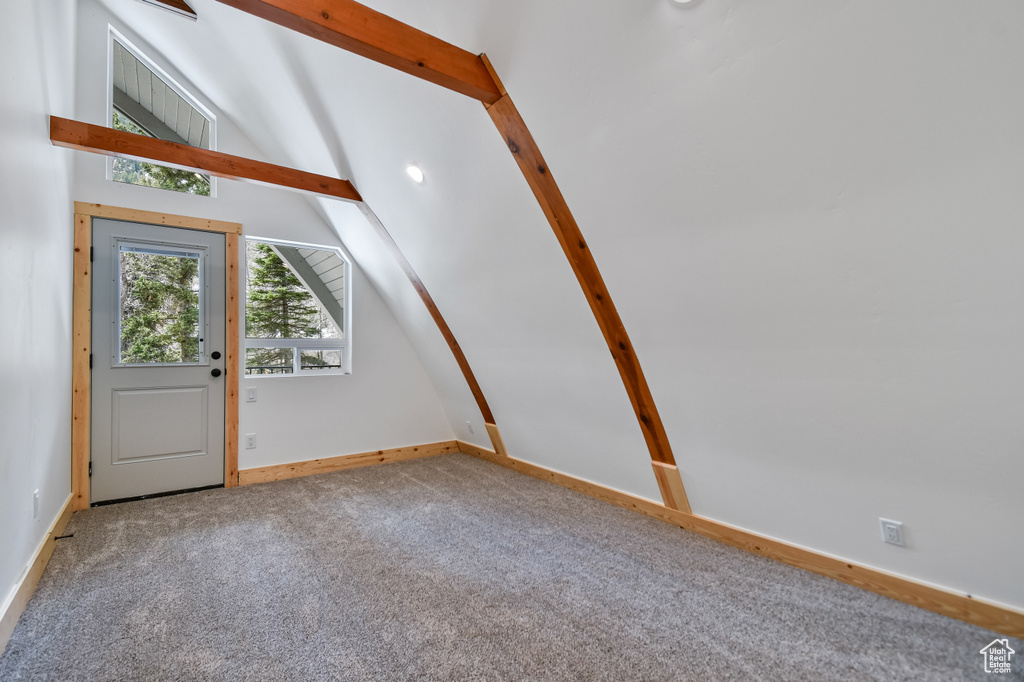 Entrance foyer featuring baseboards, lofted ceiling with beams, and carpet flooring