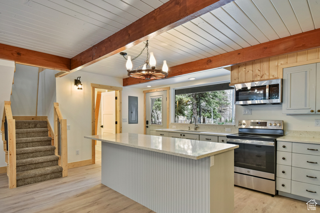 Kitchen featuring light wood-style floors, a sink, appliances with stainless steel finishes, and beamed ceiling