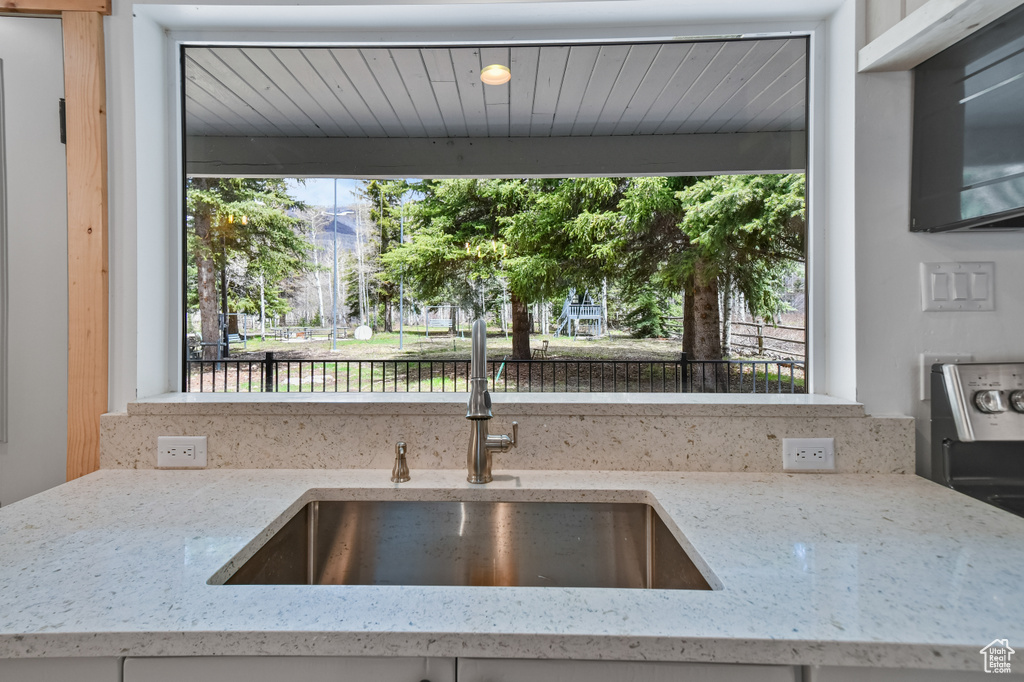 Kitchen with a sink, light stone countertops, and a wealth of natural light