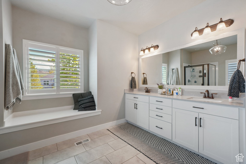 Full bath featuring a sink, tile patterned flooring, double vanity, a shower stall, and visible vents