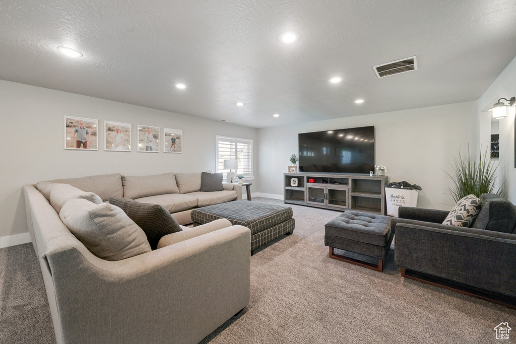 Carpeted living area with recessed lighting, baseboards, and visible vents