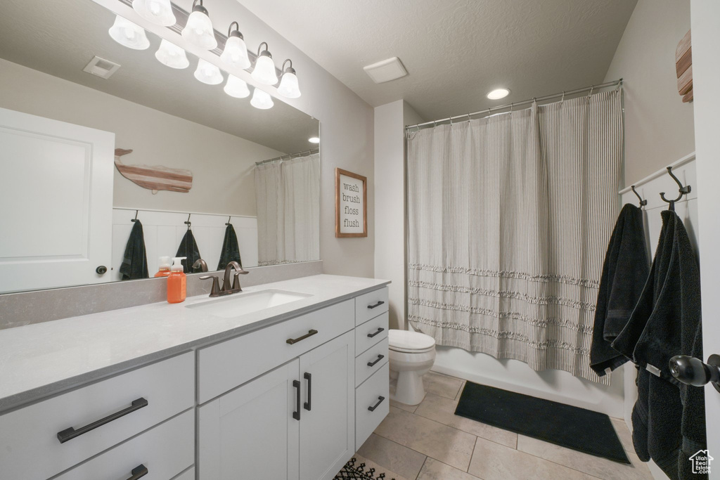 Full bathroom with shower / bath combination with curtain, visible vents, tile patterned floors, vanity, and toilet