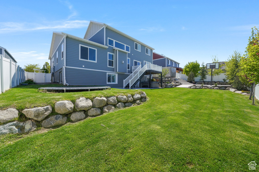 Rear view of house featuring a fenced backyard, stairs, a lawn, and a deck