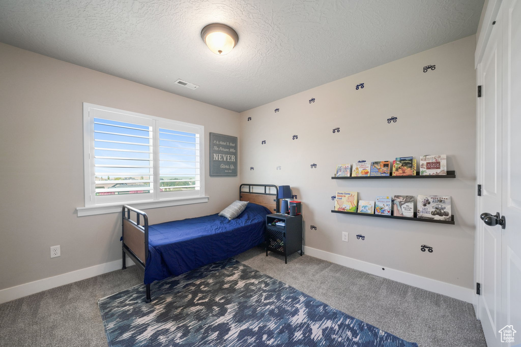 Carpeted bedroom featuring a textured ceiling, visible vents, and baseboards