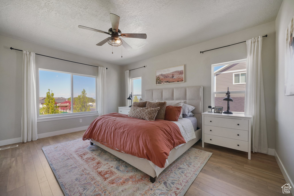 Bedroom with baseboards, light wood-style flooring, and visible vents