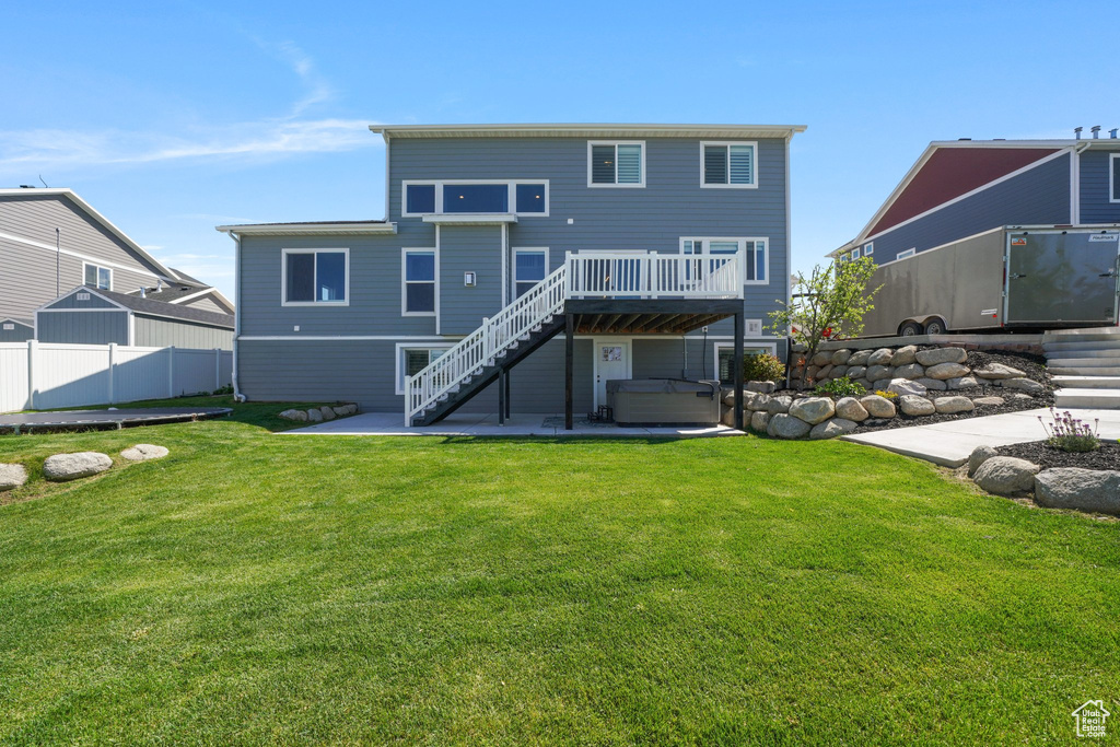Back of house featuring fence, a patio, stairs, a lawn, and a hot tub