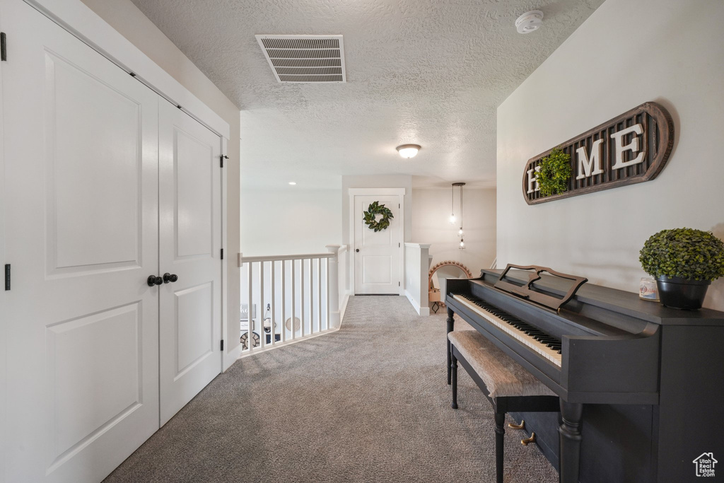 Hallway featuring carpet, a textured ceiling, and visible vents