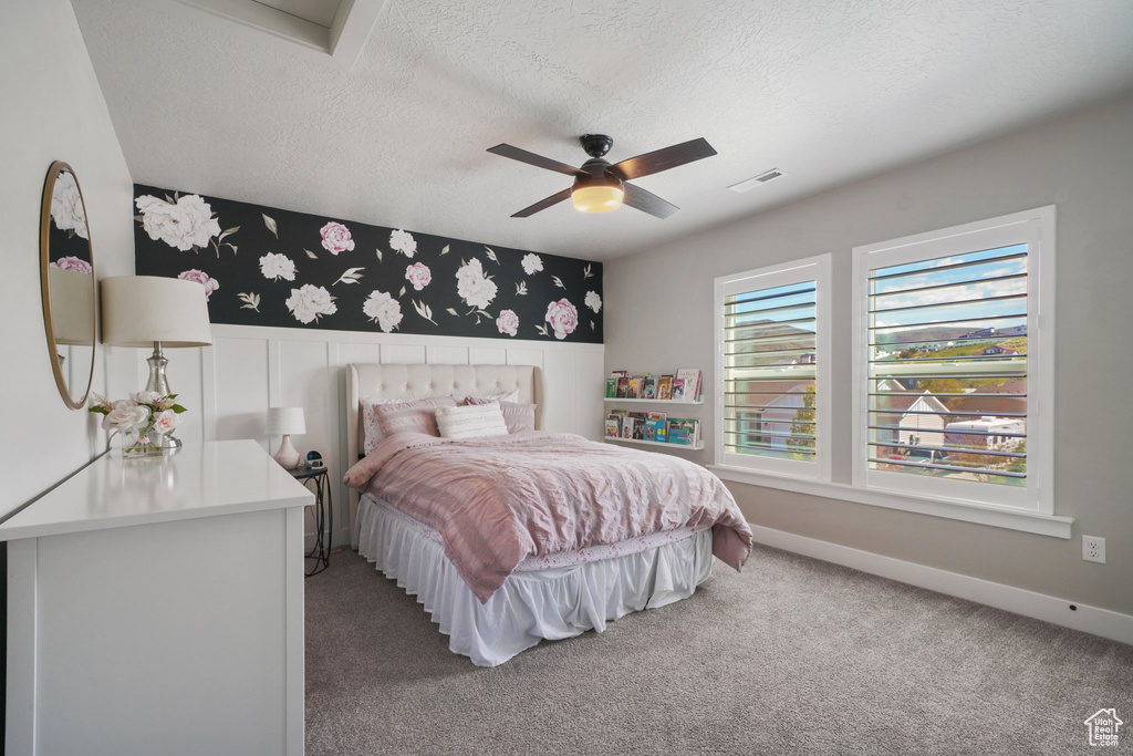Bedroom featuring ceiling fan, a textured ceiling, visible vents, carpet flooring, and wallpapered walls