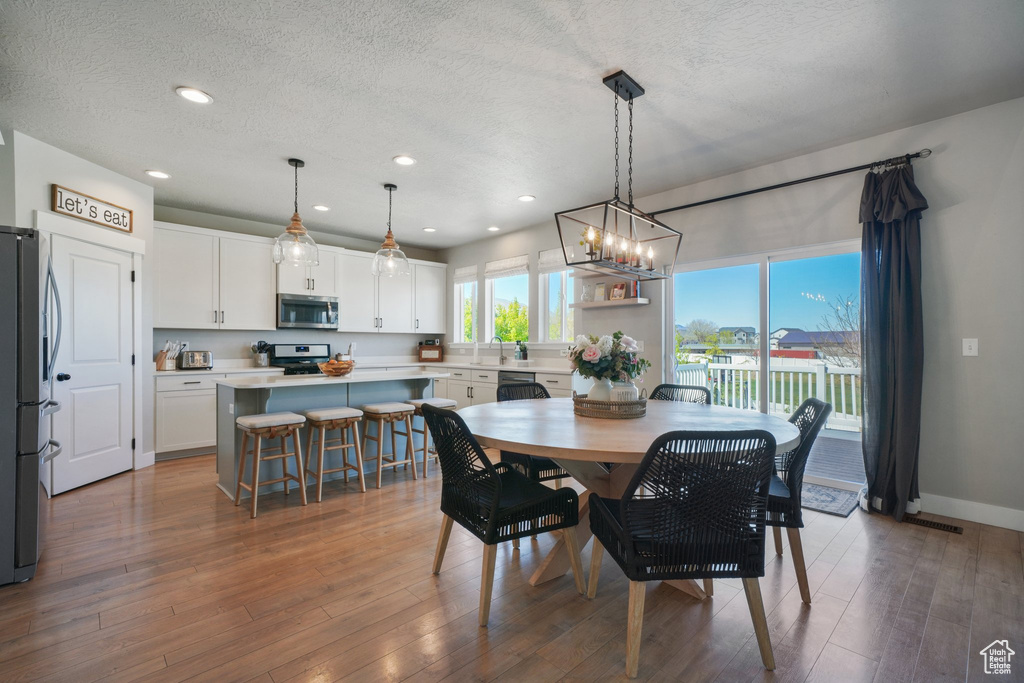 Dining space featuring a textured ceiling, wood finished floors, baseboards, an inviting chandelier, and recessed lighting