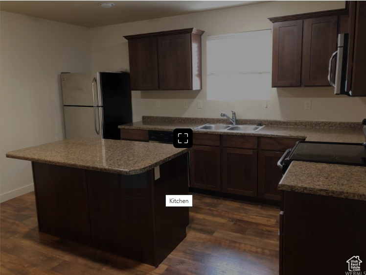 Kitchen with dark brown cabinetry, a kitchen island, dark wood-style floors, a sink, and stainless steel appliances