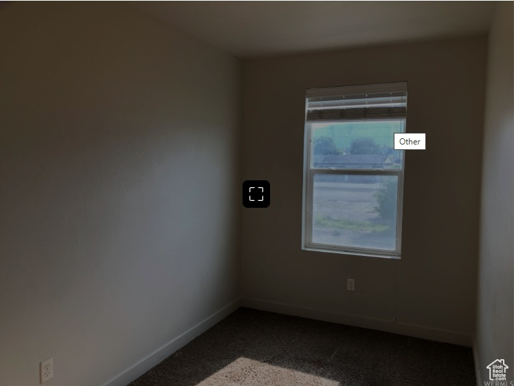 Spare room with baseboards and dark colored carpet