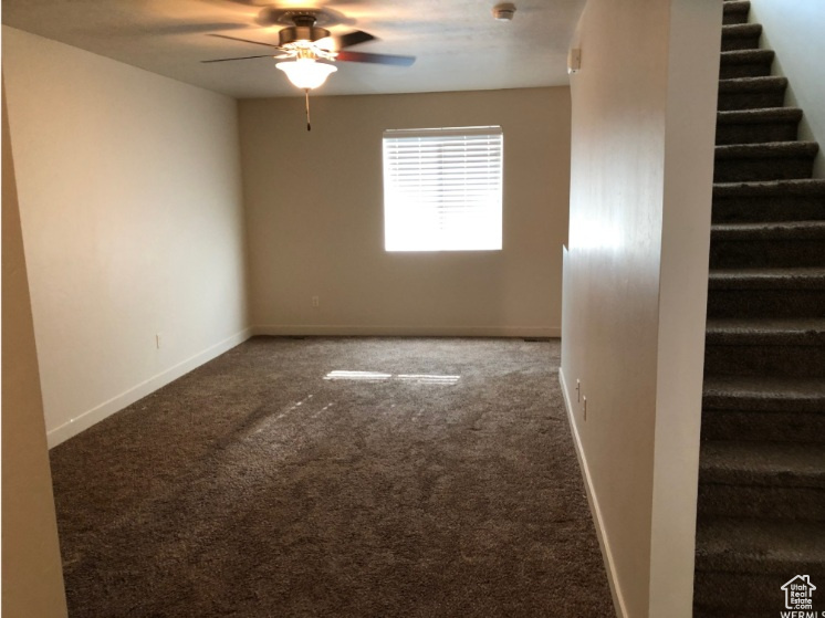 Unfurnished room featuring stairway, baseboards, ceiling fan, and carpet flooring