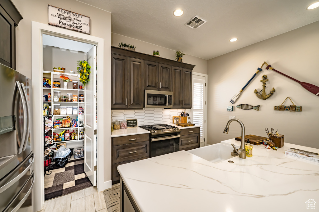 Kitchen with visible vents, dark brown cabinets, recessed lighting, a sink, and appliances with stainless steel finishes