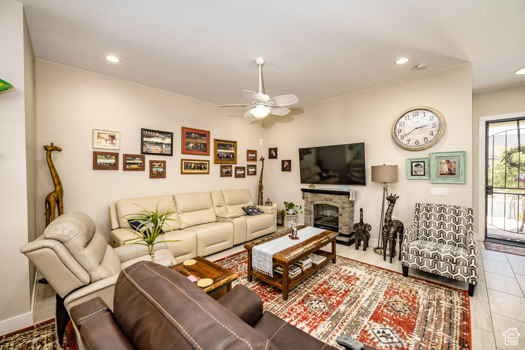 Tiled living room featuring recessed lighting, a ceiling fan, baseboards, and a stone fireplace