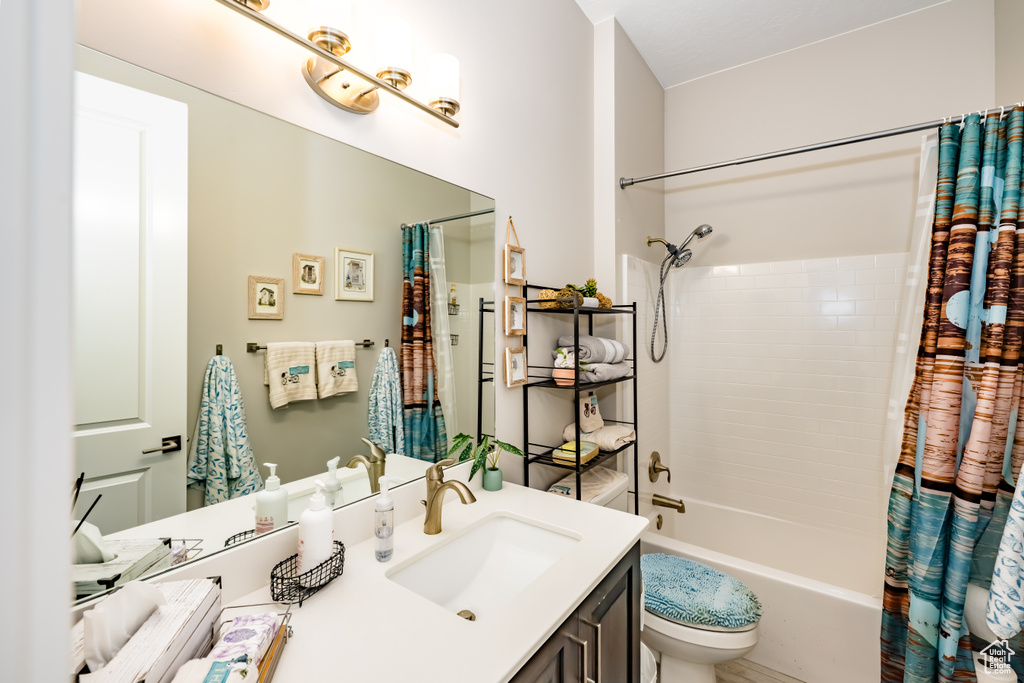 Bathroom featuring vanity, toilet, and shower / bathtub combination with curtain