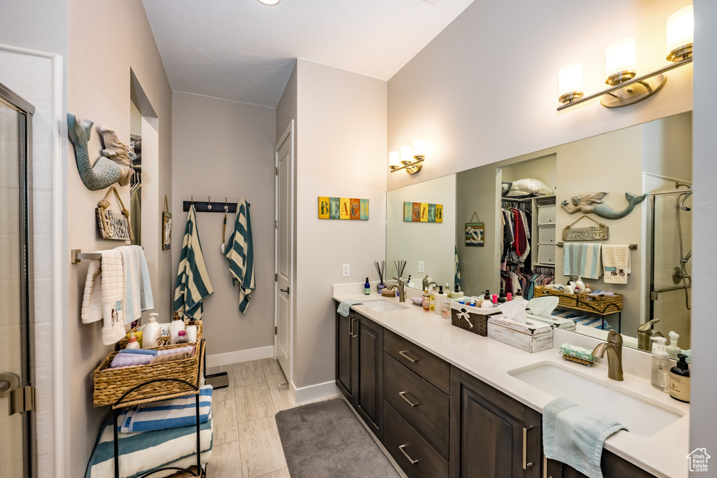 Bathroom with a sink, a stall shower, and double vanity