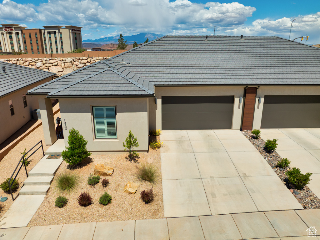View of front of property featuring a mountain view, stucco siding, a tile roof, and concrete driveway