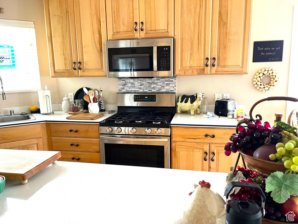Kitchen with light countertops, stainless steel appliances, a sink, and tasteful backsplash