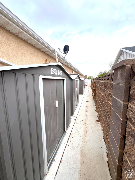 View of property exterior featuring fence, an outbuilding, a shed, and stucco siding