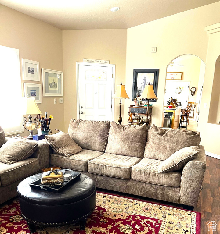 Living area with arched walkways, baseboards, and dark wood finished floors
