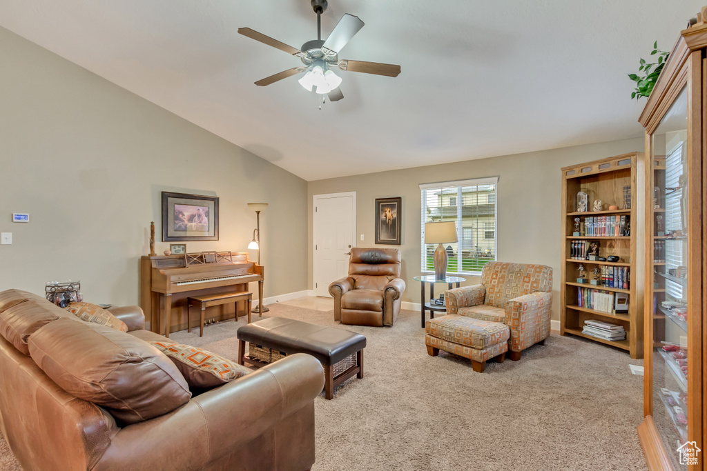 Carpeted living room with ceiling fan, vaulted ceiling, and baseboards