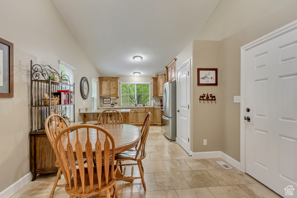 Dining space with light tile patterned floors, lofted ceiling, visible vents, and baseboards