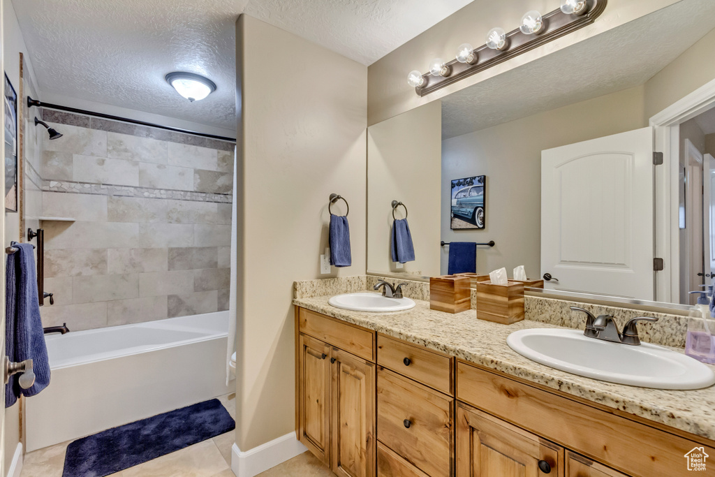 Full bathroom with a sink, a textured ceiling, and double vanity