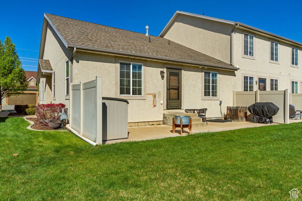 Back of property with a yard, a patio area, stucco siding, and fence