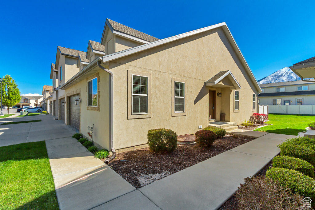 View of front of property with roof with shingles, a front lawn, stucco siding, and fence