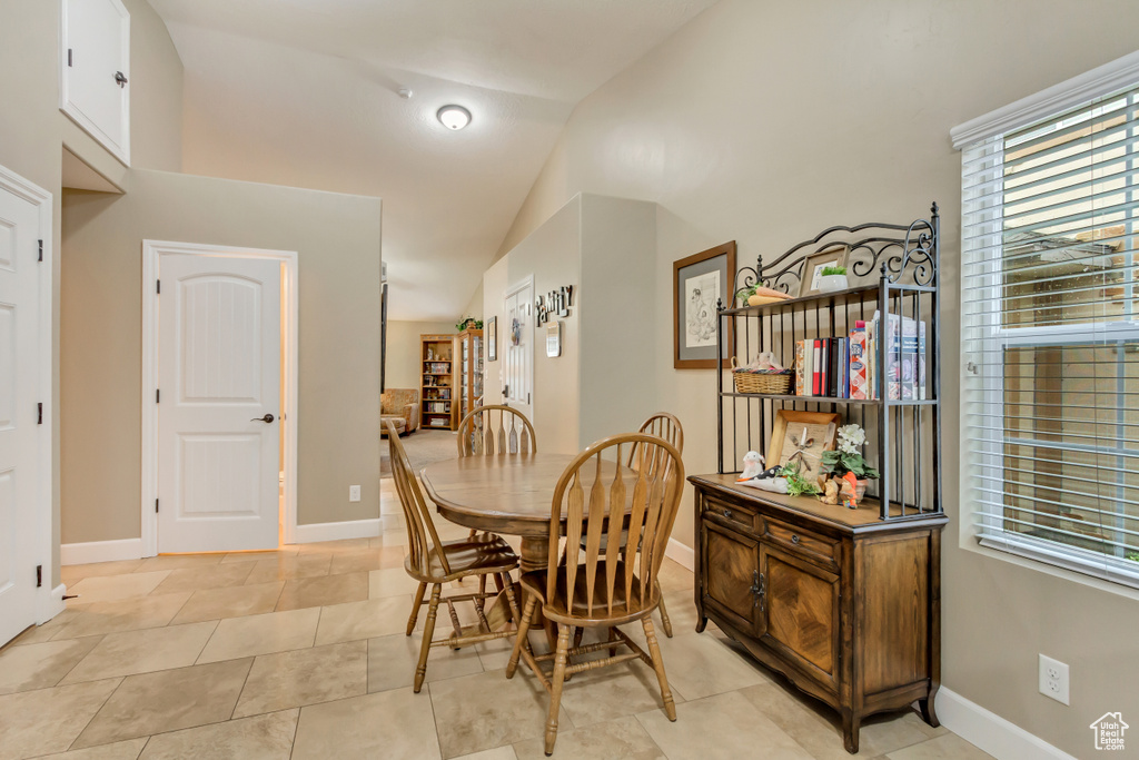 Dining space featuring lofted ceiling, baseboards, and light tile patterned floors