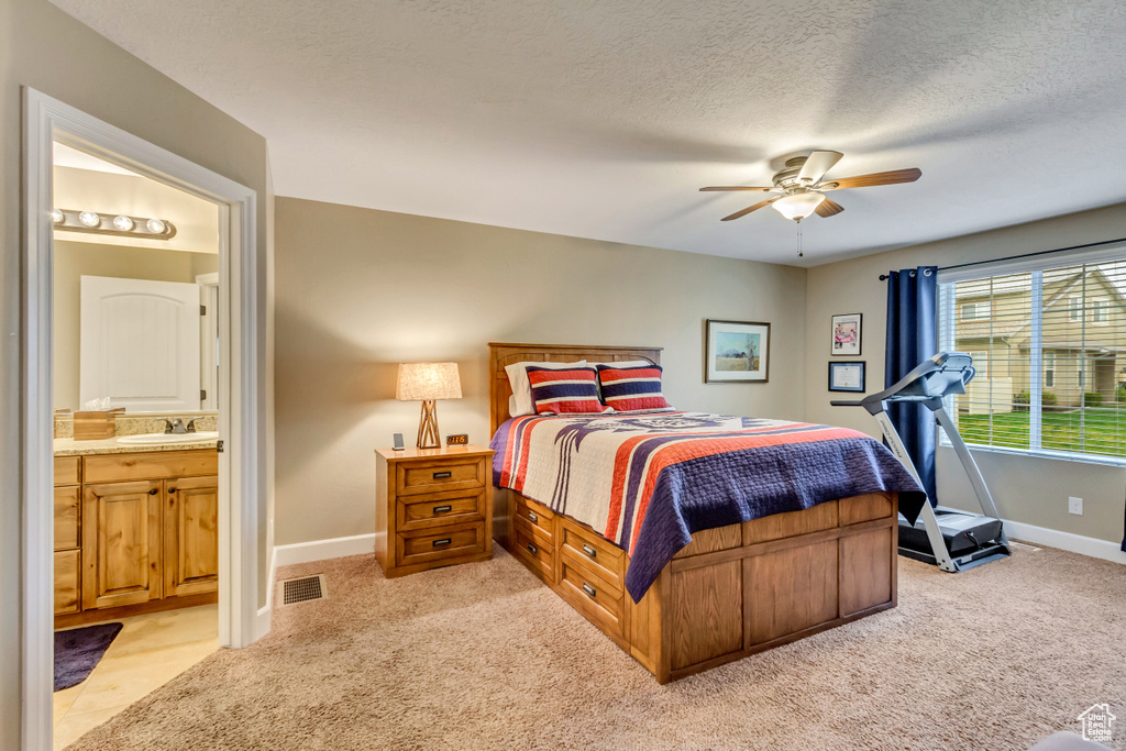 Bedroom with a sink, connected bathroom, light colored carpet, baseboards, and visible vents