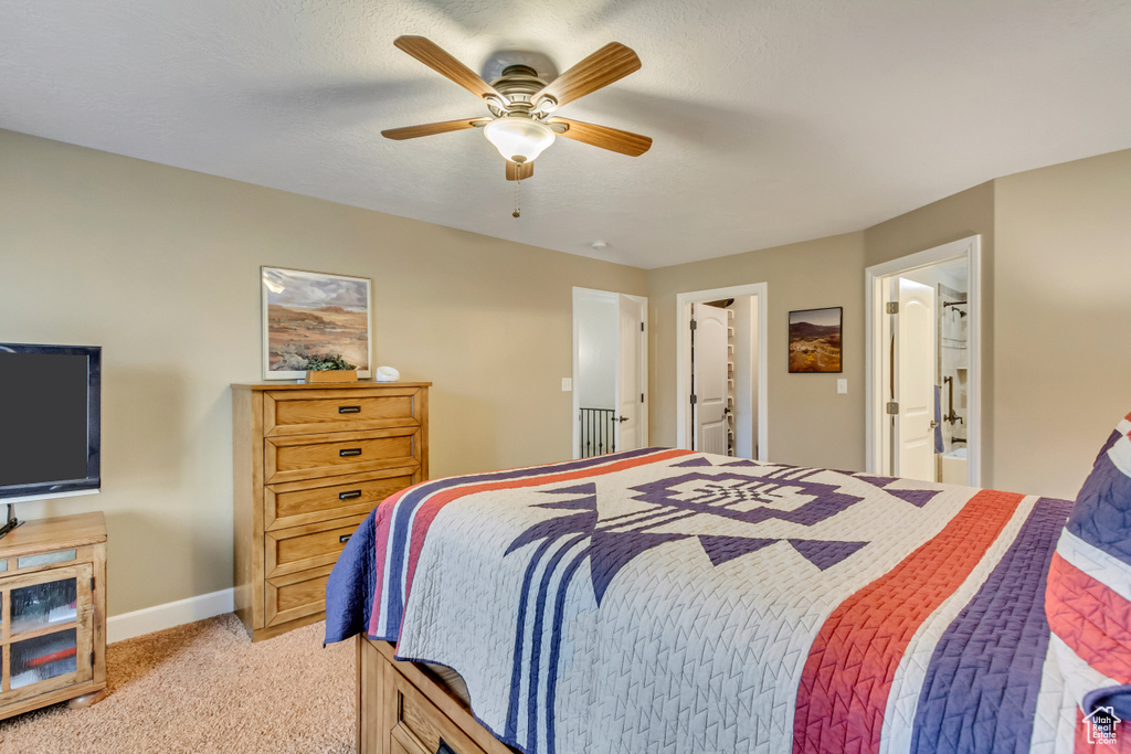 Bedroom with light colored carpet, ceiling fan, baseboards, and connected bathroom