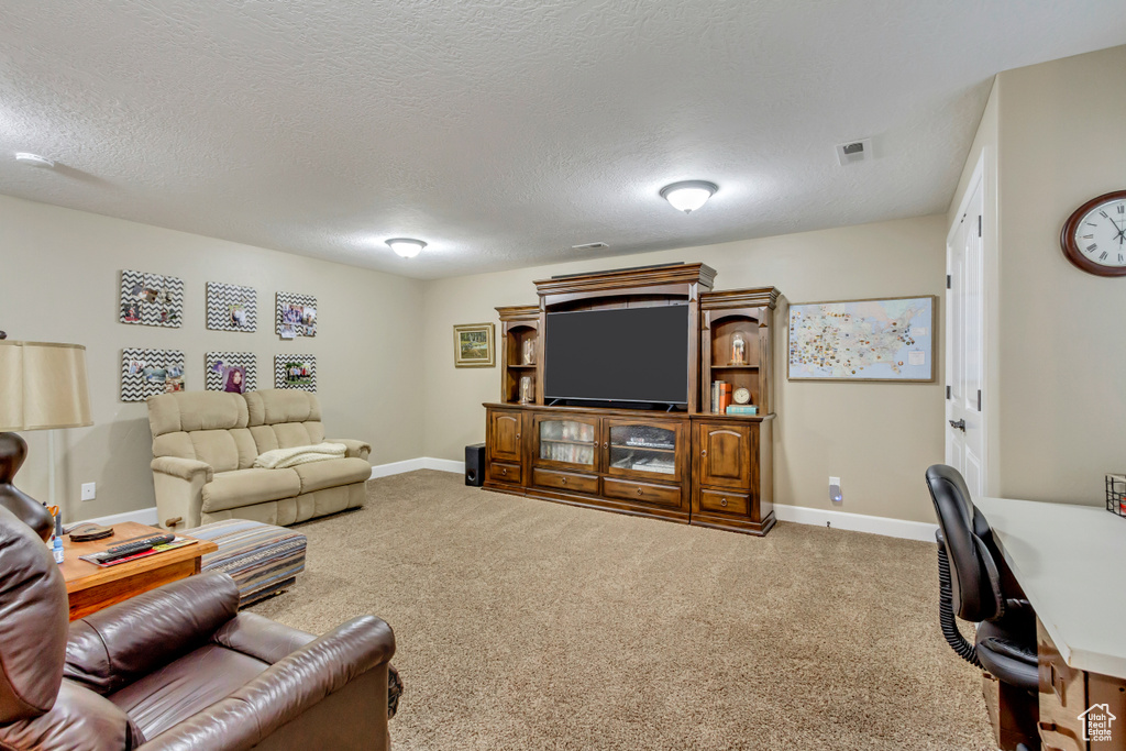 Living room featuring baseboards, a textured ceiling, visible vents, and carpet