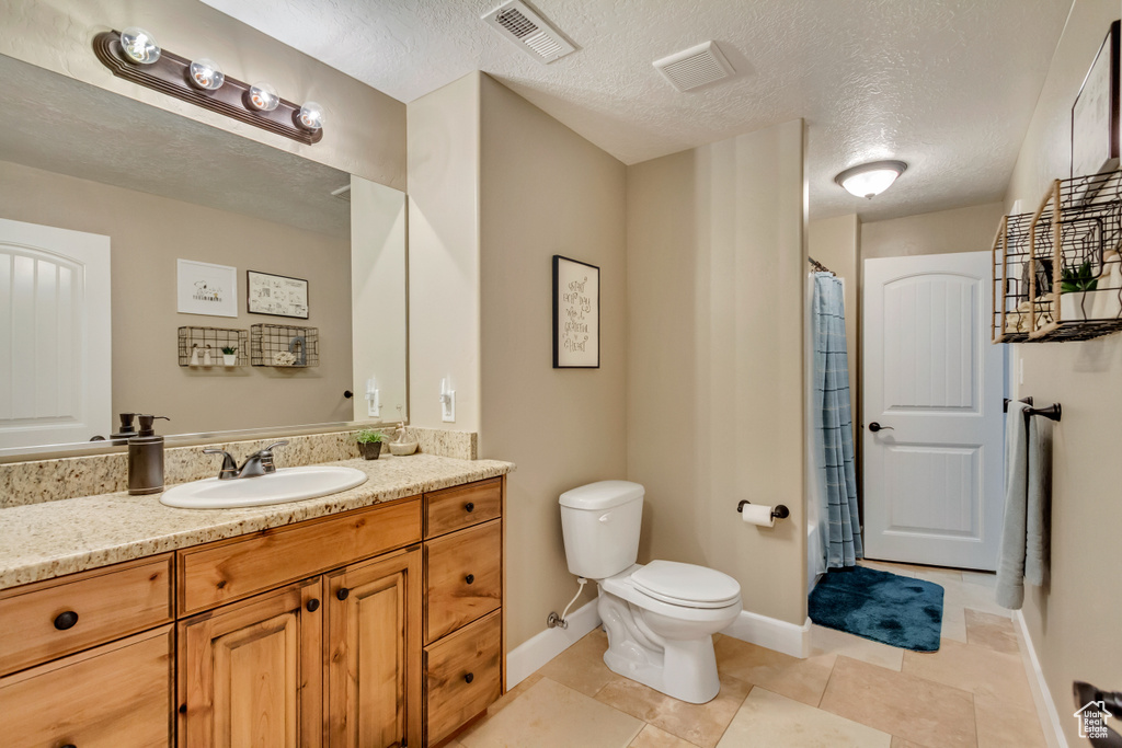 Full bath featuring toilet, vanity, tile patterned floors, and a textured ceiling