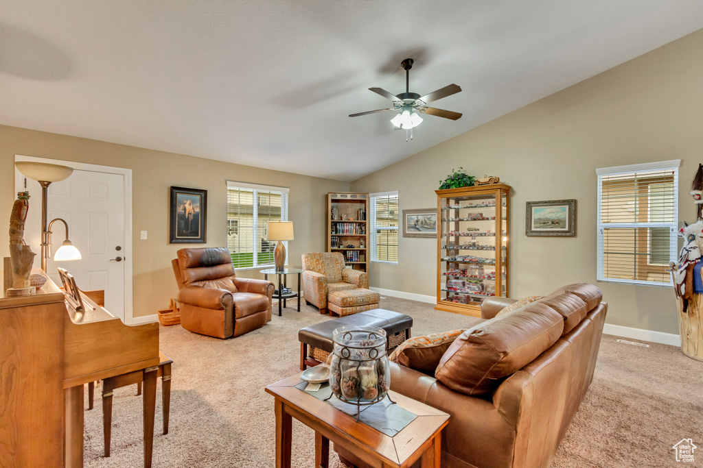 Living room featuring ceiling fan, light carpet, vaulted ceiling, and baseboards