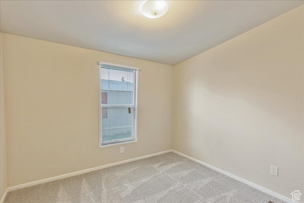 Empty room featuring baseboards and light carpet