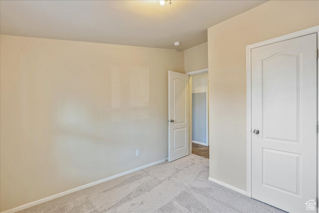 Unfurnished bedroom with baseboards and light colored carpet